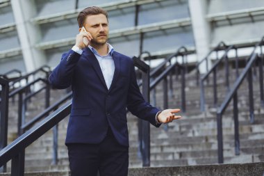 Açık havada, cep telefonundan bir işadamı konuşurken iş elbiseli bir adam