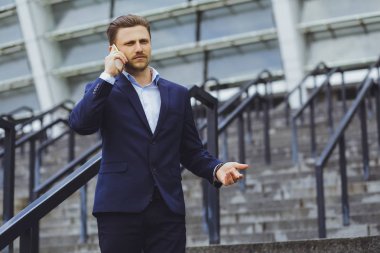 Açık havada, cep telefonundan bir işadamı konuşurken iş elbiseli bir adam