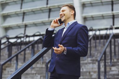 Açık havada, cep telefonundan bir işadamı konuşurken iş elbiseli bir adam