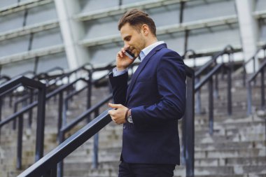 Açık havada, cep telefonundan bir işadamı konuşurken iş elbiseli bir adam