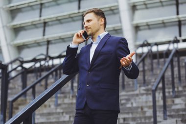 Açık havada, cep telefonundan bir işadamı konuşurken iş elbiseli bir adam