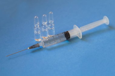 Tıbbi şırınga, mavi arka plan üzerinde ampul