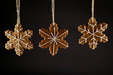 Bir ip üzerinde siyah bir arka plan asılı Noel gingerbread çerezleri kar tanesi. Noel arka plan