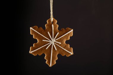 Bir ip üzerinde siyah bir arka plan asılı Noel gingerbread çerezleri kar tanesi. Noel arka plan