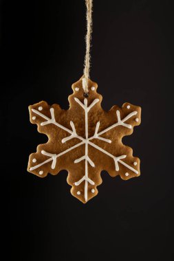 Bir ip üzerinde siyah bir arka plan asılı Noel gingerbread çerezleri kar tanesi. Noel arka plan