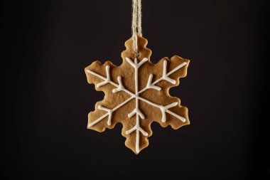 Bir ip üzerinde siyah bir arka plan asılı Noel gingerbread çerezleri kar tanesi. Noel arka plan