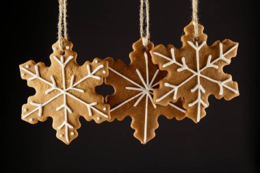 Bir ip üzerinde siyah bir arka plan asılı Noel gingerbread çerezleri kar tanesi. Noel arka plan