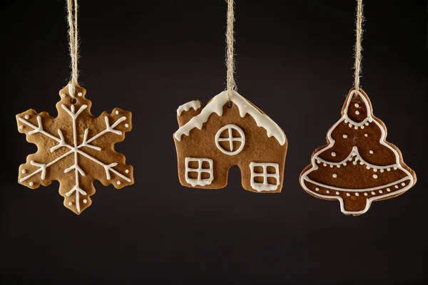 Noel gingerbread çerezleri bir ip üzerinde siyah bir arka plan asılı. Noel arka plan