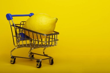 Alışveriş arabası sarı zemin üzerine alışveriş sepeti, limon