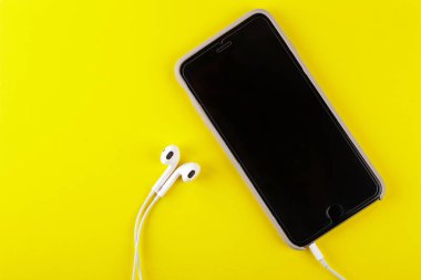 cep telefonu akıllı telefon kulaklık sarı zemin üzerine. üstten görünüm kopya alanı