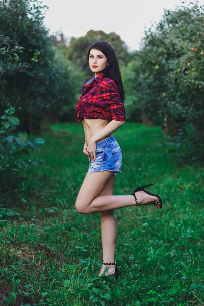 Şort ve tişört arka plan yeşil çim üzerinde yaz parkta genç güzel esmer kız