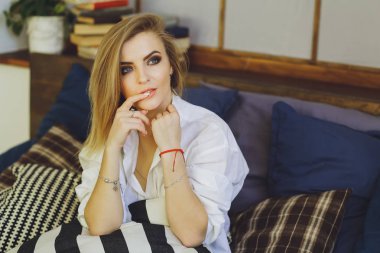 Genç güzel sarışın kız yatakta bir beyaz erkek gömlek