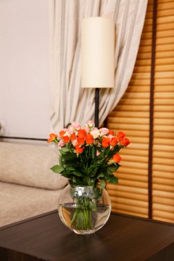 Bir vazo içindeki bir buket çiçek odanın içindeki bir sehpanın üzerinde.