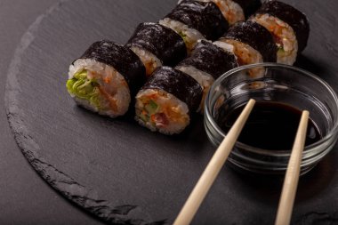 Siyah arka planda wasabi zencefil ve soya soslu suşi rulosu.