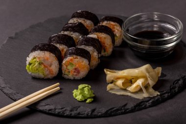 Siyah arka planda wasabi zencefil ve soya soslu suşi rulosu.