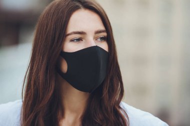 COVID-19 Pandemik Coronavirüs. Şehir caddesinde yüzüne virüs bulaşan koruyucu maskeli bir kız. Tıbbi maskeli kız.