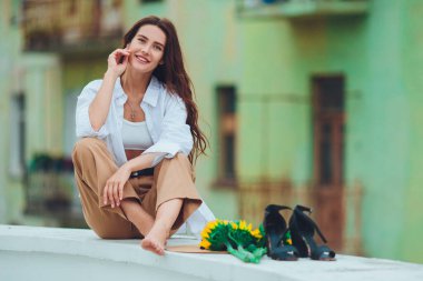 Şehirde, şapkalı, siyah saçlı güzel bir kadın bir buket ayçiçeği için el ele tutuşuyor ve başka tarafa bakıyor. Şık ve şık bir kız.