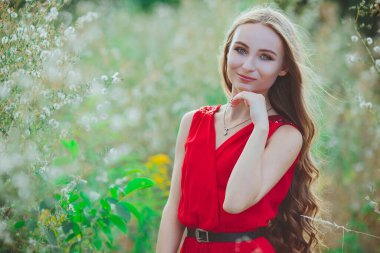 Açık arazide kırmızı elbiseli güzel bir kızın portresi.