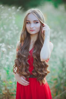 Açık arazide kırmızı elbiseli güzel bir kızın portresi.