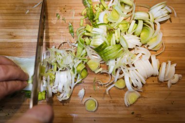 Ahşap kesme tahtası üzerinde bıçakla adam kesme pırasa görünümünü kapat