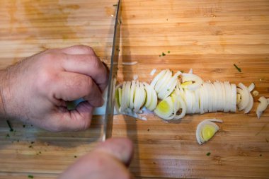 Ahşap kesme tahtası üzerinde bıçakla adam kesme pırasa görünümünü kapat