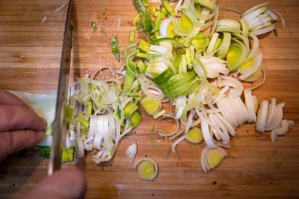 Ahşap kesme tahtası üzerinde bıçakla adam kesme pırasa görünümünü kapat