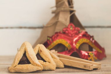 Purim Yahudi Bayramı kompozisyon hamantaschen, purim maskesi ile purim gragger kopya spac bir vintage ahşap zemin üzerine