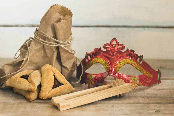 Purim Yahudi Bayramı kompozisyon hamantaschen, purim maskesi ile purim gragger kopya spac bir vintage ahşap zemin üzerine