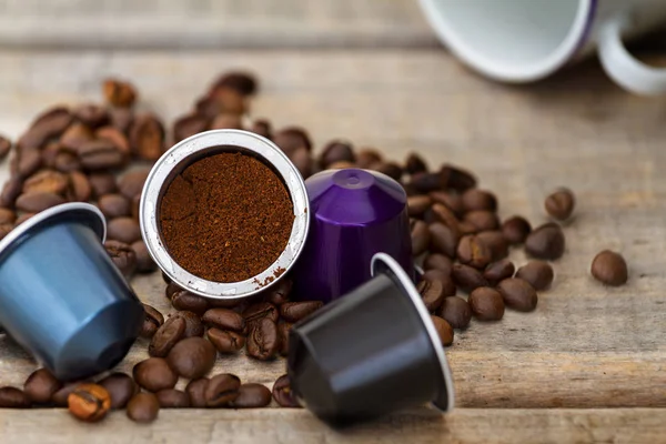 Italian espresso coffee capsules or coffee pods on wood background with some roasted coffee beans