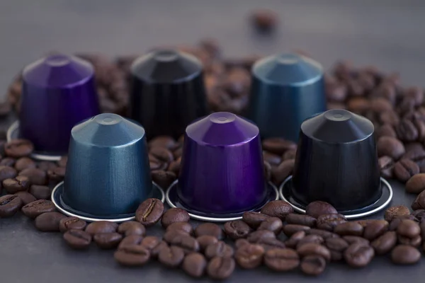 Italian espresso coffee capsules or coffee pods on a dark stone or marble  background with some roasted coffee beans