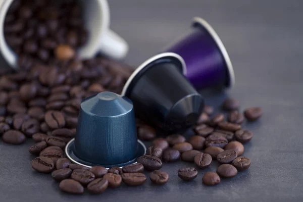 イタリアンエスプレッソ コーヒー カプセルまたは暗い石や大理石の背景にいくつかコーヒー豆の焙煎のコーヒーのポッド ストックフォト