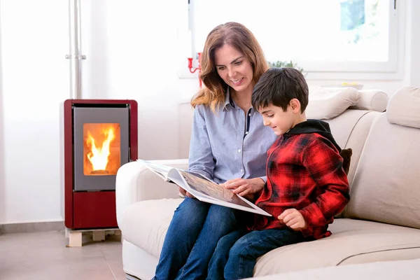 Mother Her Son Read Book Winter Setting Stove Sitting Sofa — Stock Photo, Image