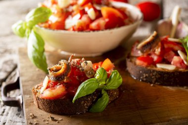 Lezzetli İtalyan aperatifleri bruschetta, bir dilim ekmek garnitürlü domates fesleğeni, ahşap tahtaya yakın.