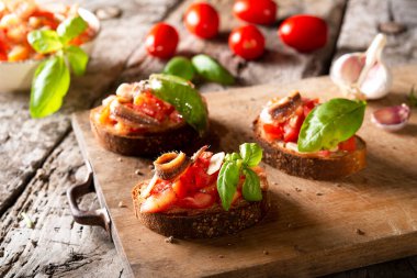Tahtada domates, fesleğen ançüez ve zeytinyağı olsun. Geleneksel İtalyan aperatifi veya aperatifi, antipasto.