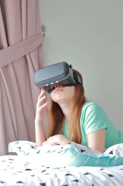 Evde sanal gerçeklik gözlüklü genç kadın. Bir sanal gerçeklik kulaklık takan için sanal gerçeklik sağlar başa takılan bir aygıt olduğunu.
