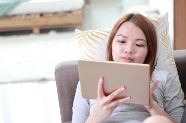 Evde tablet kullanan genç kadın. Bir tablet bir defter daha küçük ama bir akıllı telefon daha büyük bir kablosuz dokunmatik ekran kişisel bilgisayar olduğunu.