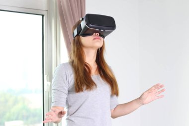 Evde sanal gerçeklik gözlüklü genç kadın. Bir sanal gerçeklik kulaklık takan için sanal gerçeklik sağlar başa takılan bir aygıt olduğunu.