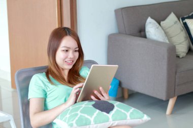 Evde tablet kullanan genç kadın. Bir tablet bir defter daha küçük ama bir akıllı telefon daha büyük bir kablosuz dokunmatik ekran kişisel bilgisayar olduğunu.