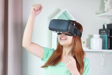 Evde sanal gerçeklik gözlüklü genç kadın. Bir sanal gerçeklik kulaklık takan için sanal gerçeklik sağlar başa takılan bir aygıt olduğunu.