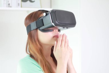 Evde sanal gerçeklik gözlüklü genç kadın. Bir sanal gerçeklik kulaklık takan için sanal gerçeklik sağlar başa takılan bir aygıt olduğunu.