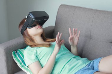 Evde sanal gerçeklik gözlüklü genç kadın. Bir sanal gerçeklik kulaklık takan için sanal gerçeklik sağlar başa takılan bir aygıt olduğunu.