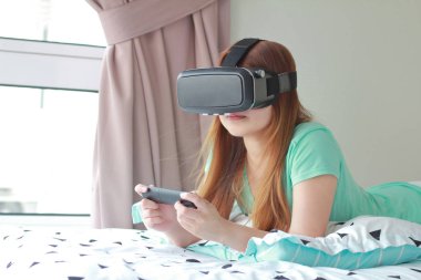 Evde sanal gerçeklik gözlüklü genç kadın. Bir sanal gerçeklik kulaklık takan için sanal gerçeklik sağlar başa takılan bir aygıt olduğunu.