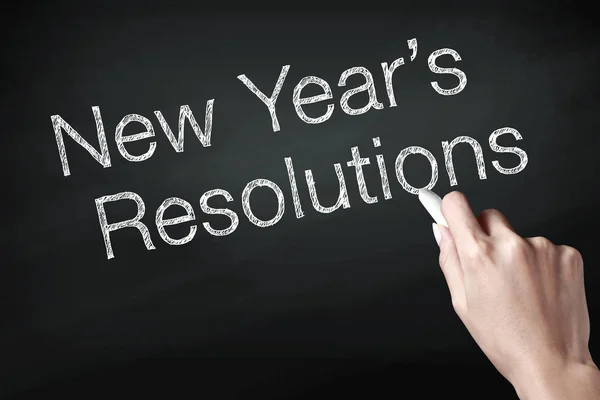 Hand holding a chalk and writing new year resolution, wish you all the best as always in this coming new year.