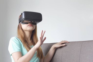 Evde sanal gerçeklik gözlüklü genç kadın. Bir sanal gerçeklik kulaklık takan için sanal gerçeklik sağlar başa takılan bir aygıt olduğunu.