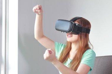 Evde sanal gerçeklik gözlüklü genç kadın.