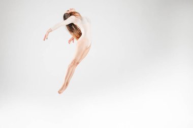 Beyaz arka planda parlak giysiler içinde zıplayan dansçı. Zıpla, uç, hava, güzel, poz ver
