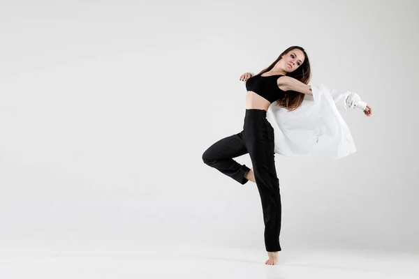 Female dancer in dance jazz poses in a shirt on a white background. Jazz, modern, freedom, feelings, sport, figure, dance.