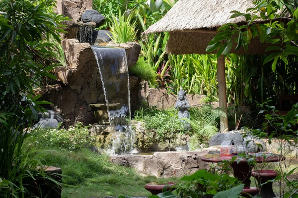 Tropik bölgelerde güzel bir avlu. Dış, yeşillik, şelale, heykeller, orman, saman şemsiye, dinlenme, dinlenme, meditasyon