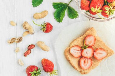 Beyaz arka planda taze çilekli fıstık ezmeli sandviç. Sağlıklı yaz kahvaltısı ya da atıştırmalık.
