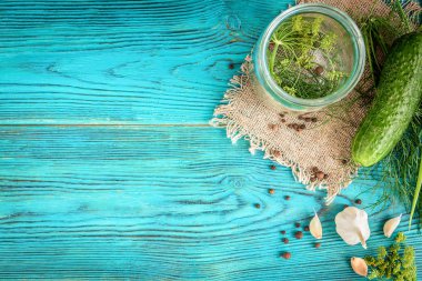 Taze salatalıklar konserve için hazır, dereotu, sarımsak ve baharatlar mavi ahşap arka planda. Salatalık turşusu..